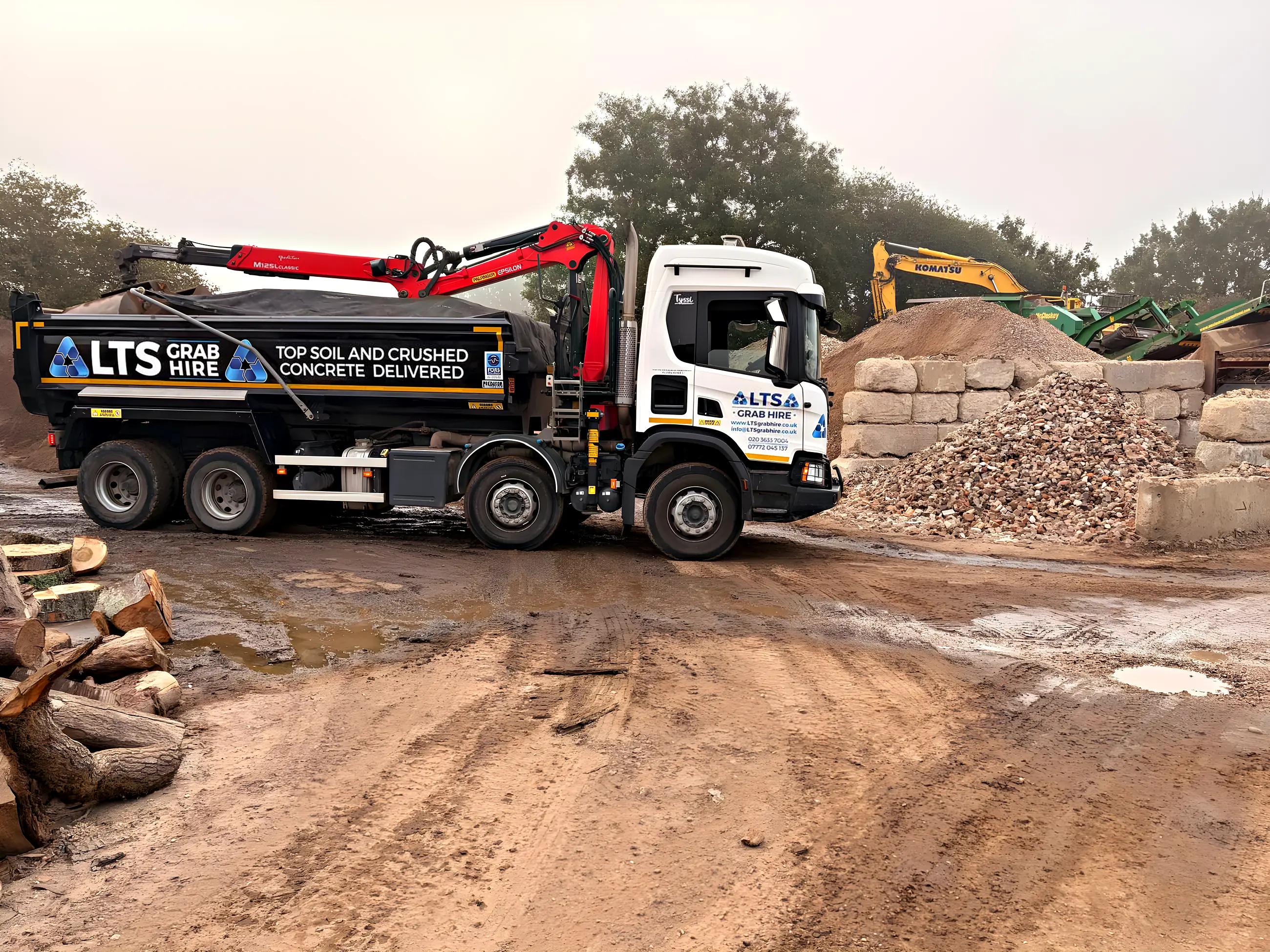 An eight-wheel grab lorry side on at the yard, lettered top soil and crushed concrete delivered